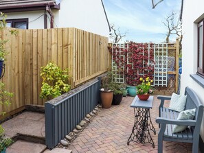 A patio with a wooden fence, potted plants, a table, and a bench. - 1 bedroom accommodation in Narberth (Narberth)