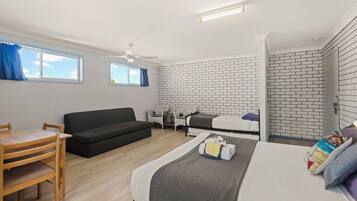 A modern room with a bed, a sofa, a dining table, and a window with curtains.