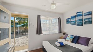 A bedroom with a bed, a window with curtains, a ceiling fan, and artwork on the wall. - Pacific Motel Evans Head (Evans Head)