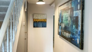 A hallway with a staircase, a radiator, and two artworks on the walls. - Elm Tree House - UK51762 (Landford, near Salisbury)