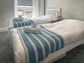 Una habitación de hotel con dos camas, una ventana con vistas, una lámpara en una mesita de noche y un enchufe.
