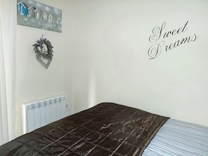 Ein Schlafzimmer mit einem Bett, einem Heizkörper, einer Wanddekoration und einem Schild mit der Aufschrift 'Sweet Dreams'.