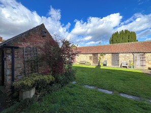 Ein Innenhof mit Steingebäuden, einer grünen Rasenfläche und blauem Himmel.