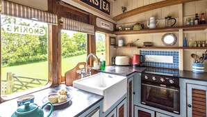 Una cocina con un lavamanos, estufa y una ventana que da a zonas verdes.