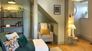 A living room with a green sofa, a patterned throw, a plaid armchair, a lamp, and a framed picture on the wall. - 2 bedroom accommodation in Lazonby, near Penrith (Lazonby, near Penrith)