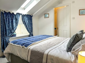 A bedroom with a bed, a window with curtains, a door, and a lamp. - The Coach House - UK51792 (Dumfries)