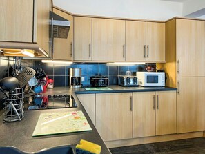 A kitchen with wooden cabinets, a coffee maker, a microwave, and a toaster. - The Coach House - UK51792 (Dumfries)