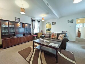 Un salon comprenant un canapé, une table basse et un meuble avec des portes en verre.