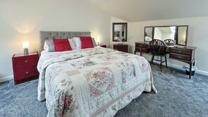 Ein Schlafzimmer mit Bett, Schreibtisch, Stuhl, Kommode und Spiegel.
