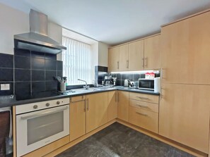 A kitchen with a stove, oven, microwave, and a window with blinds.