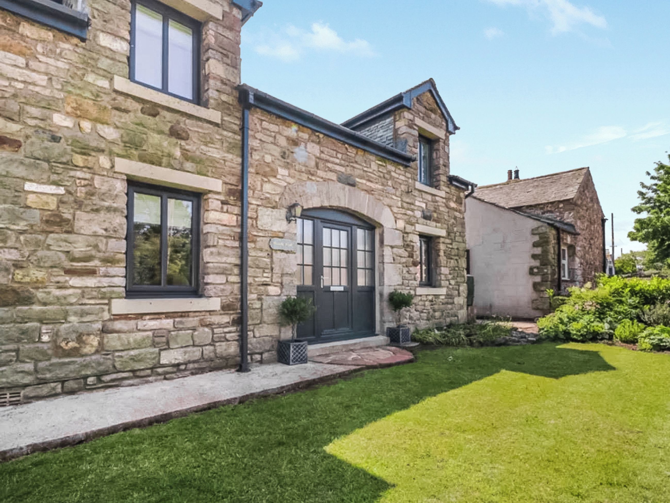 A stone building with a black door, windows, and a small garden.