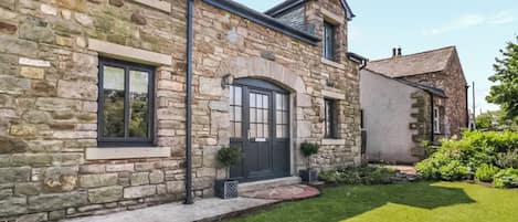 A stone building with a black door, windows, and a small garden.