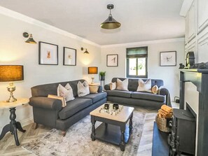 A living room with a dark grey sofa, a coffee table, and a television. - 3 bedroom accommodation in Appleby (Appleby)