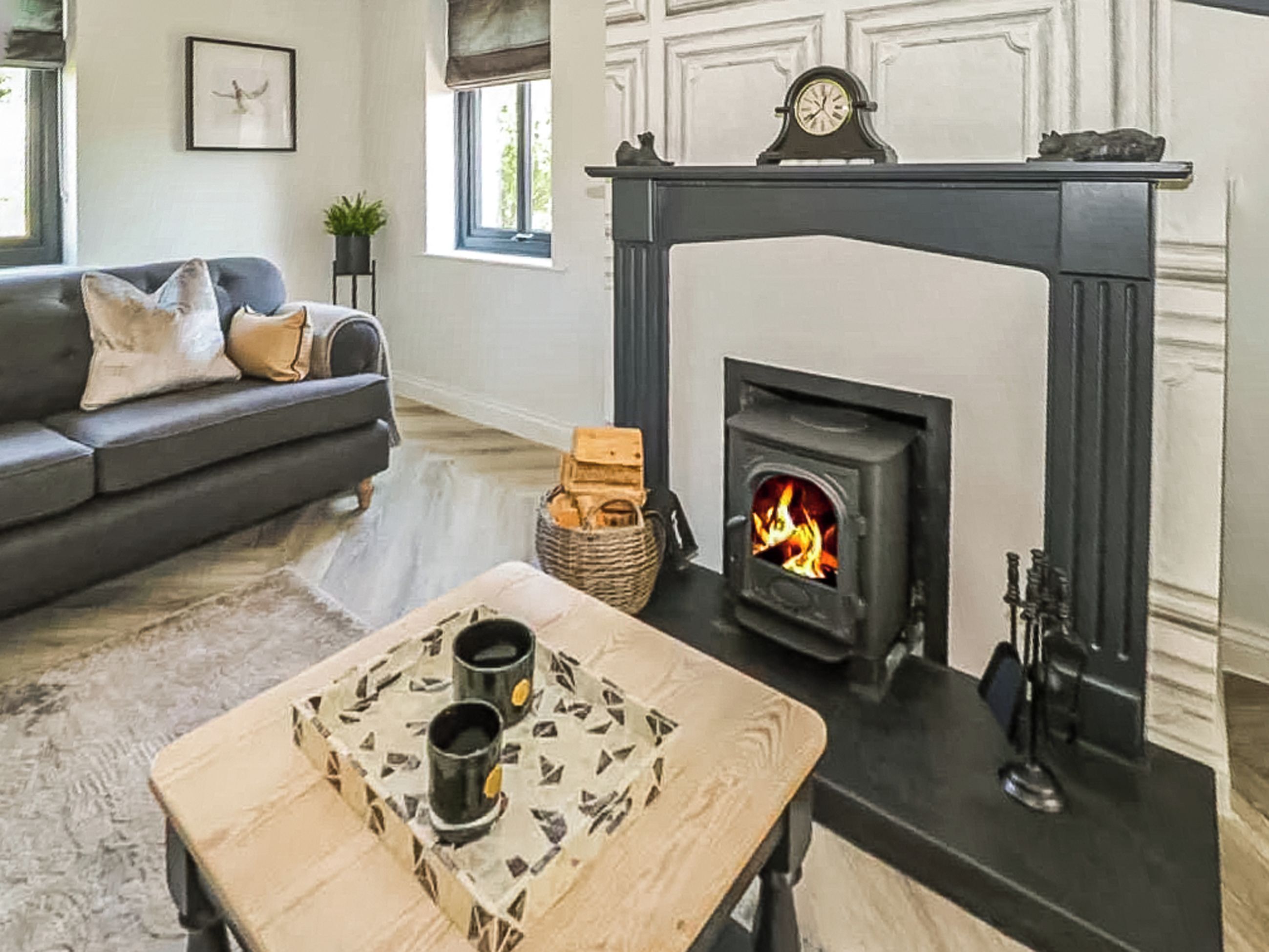 A living room with a fireplace, a sofa, a coffee table, and a clock on the mantel.