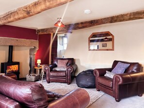 A cozy living room with a fireplace, leather sofas, and a stone wall. - 3 bedroom accommodation in Halton Gill (Halton Gill)