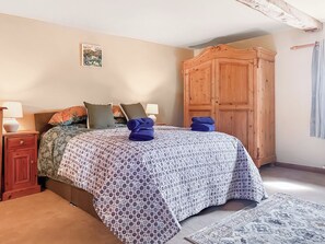 A bedroom with a bed, a wooden wardrobe, a nightstand with a lamp, and a patterned rug. - 3 bedroom accommodation in Halton Gill (Halton Gill)