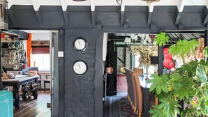 A room with a black brick wall, a wooden floor, and a dining area with chairs and a table. - 6 bedroom accommodation in Sandwich (Sandwich)