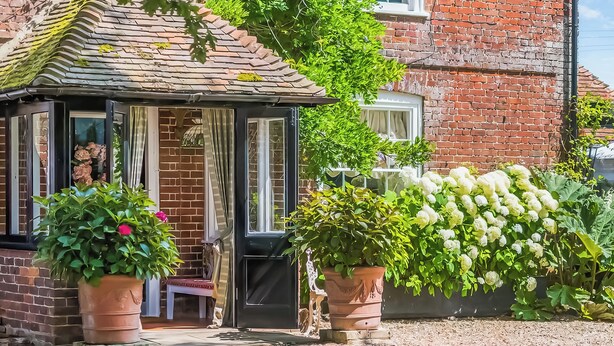 A traditional brick house with a conservatory, potted plants, and a gravel driveway. - 6 bedroom accommodation in Sandwich (Sandwich)