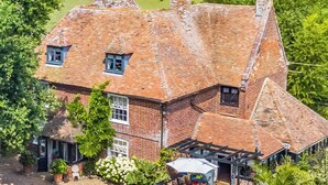 A large brick house with a sloped roof, a patio with a table and chairs, and a small garden area. - 6 bedroom accommodation in Sandwich (Sandwich)