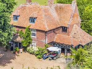 A large brick house with a sloped roof, a patio with a table and chairs, and a small garden area. - 6 bedroom accommodation in Sandwich (Sandwich)