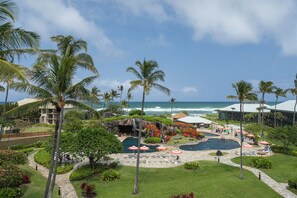 Een resort met een zwembad, palmbomen en uitzicht op de oceaan.