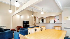 Ein modernes Wohnzimmer mit einem Holzespeisetisch, blauen Sofas und einem Flachbildfernseher.