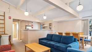 Ein modernes Wohnzimmer mit einer Couch, einem Holztisch und einem Essbereich mit Stühlen und einem Tisch.