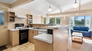 Eine moderne Küche mit eingebautem Herd, einer Spüle und einer Arbeitsplatte. Es gibt einen Essbereich mit einem blauen Sofa und einem kleinen Tisch.
