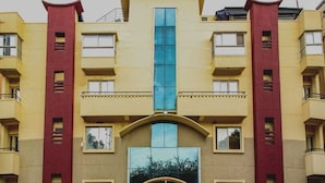 Un edifici de diversos pisos amb entrada central, balcons i façana de vidre reflectant.