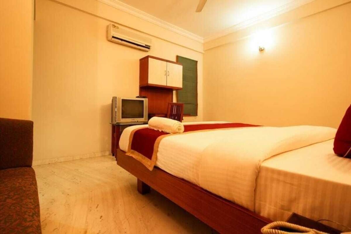 A hotel room with a bed, a television, a cabinet, and a chair.