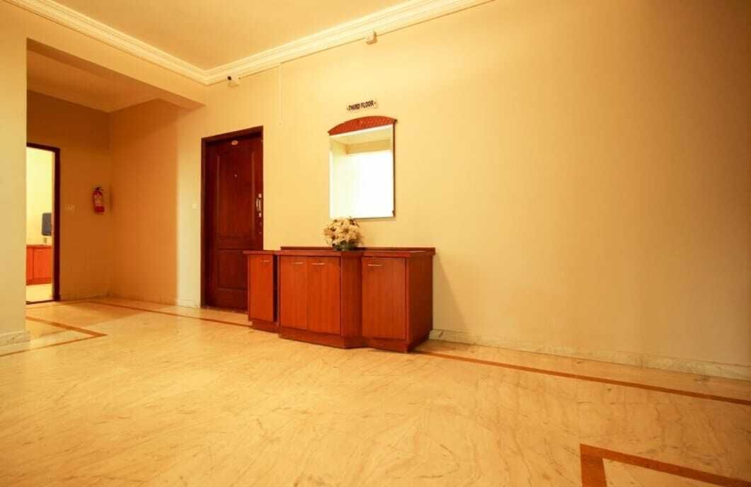 A hallway with a wooden cabinet, a door, and a wall-mounted mirror.