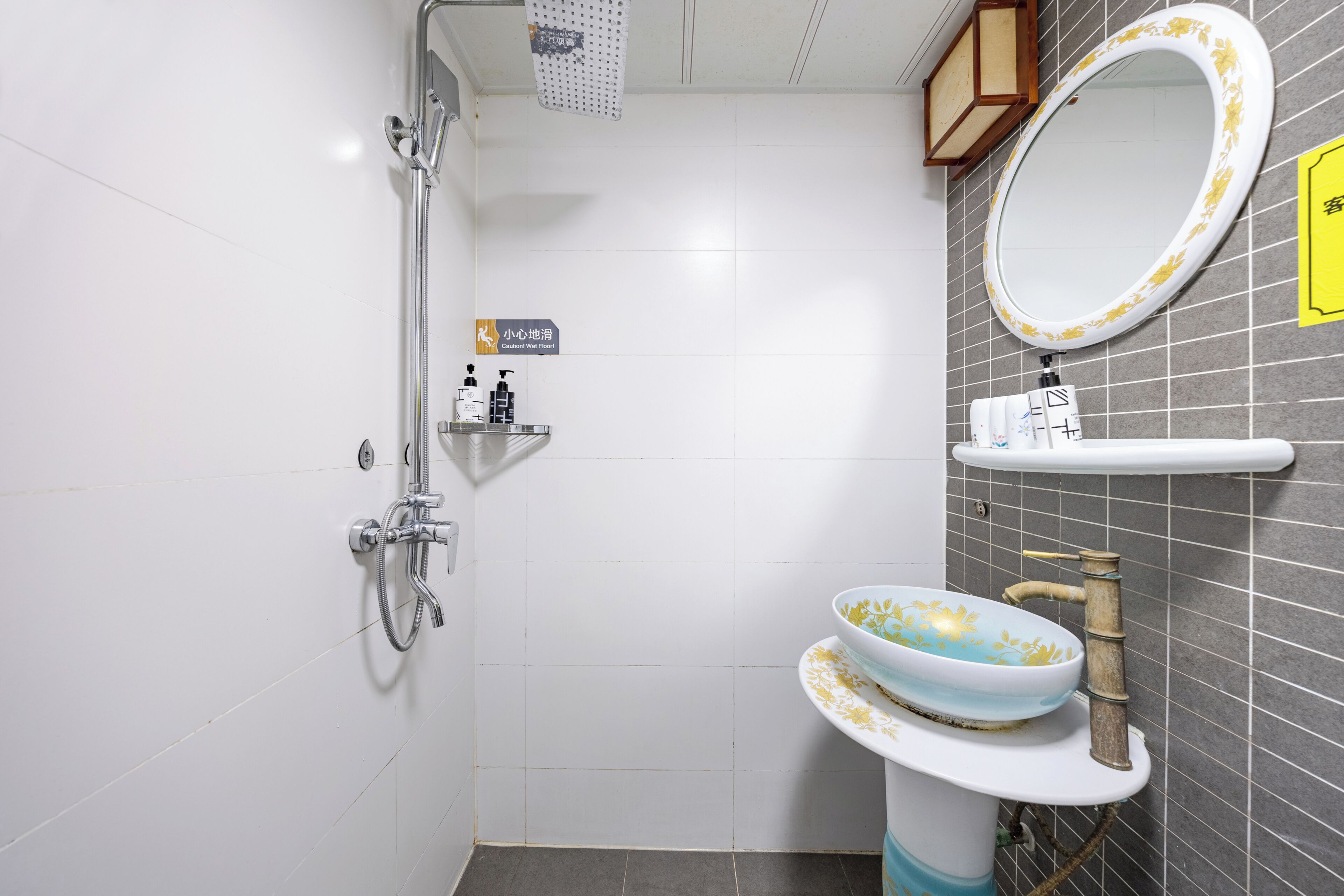 Un baño con ducha, un lavabo con un recipiente decorativo, un espejo y un estante con artículos de aseo.
