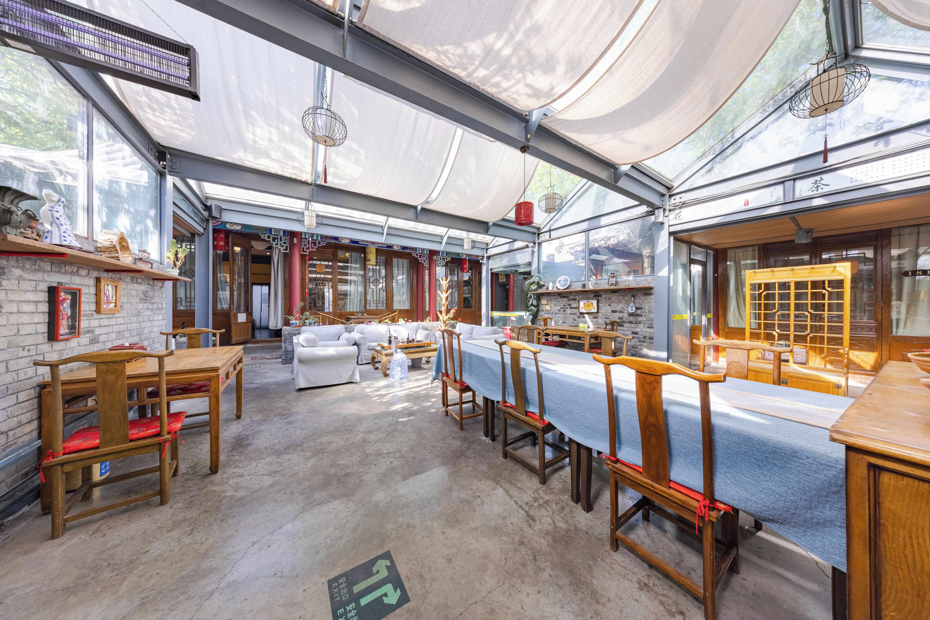 A spacious indoor area with a long table and chairs, wooden benches, and a brick wall.