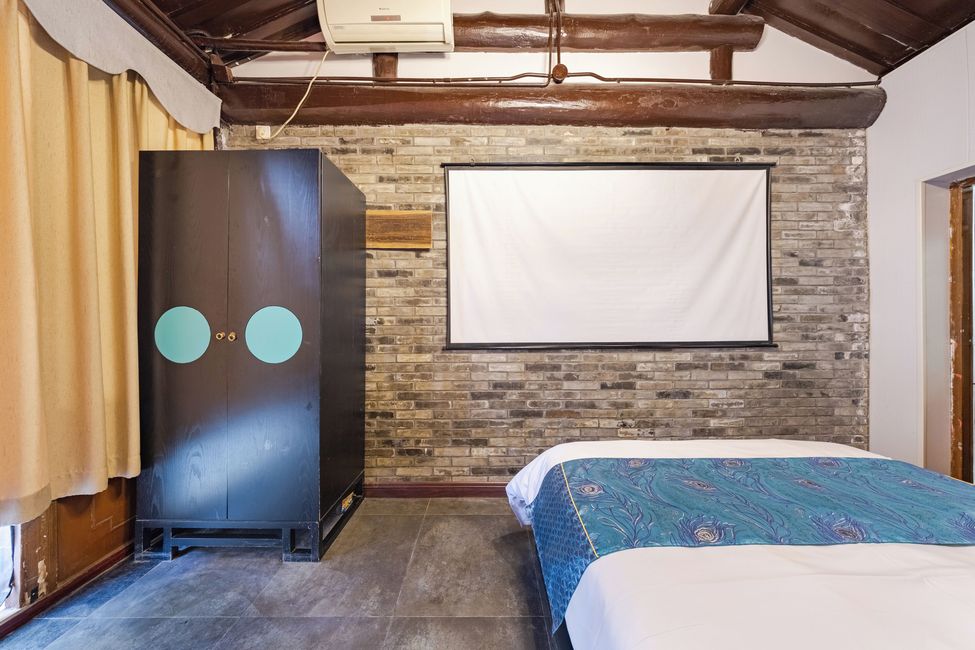 A bedroom with a bed, a wardrobe, a brick wall, and a whiteboard.