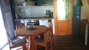 Une cuisine avec une table et des chaises en bois, un réfrigérateur et un escalier menant à un autre niveau.