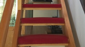 Un escalier en bois avec des marches rouges menant à un niveau supérieur.