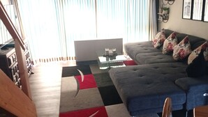 Un salon avec un canapé gris, une table basse et une lampe.