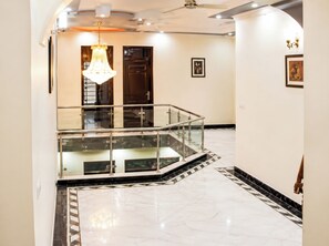 A modern interior with a glass railing, marble flooring, and a chandelier. - Hotel Maharaja Palace AGRA (Agra)