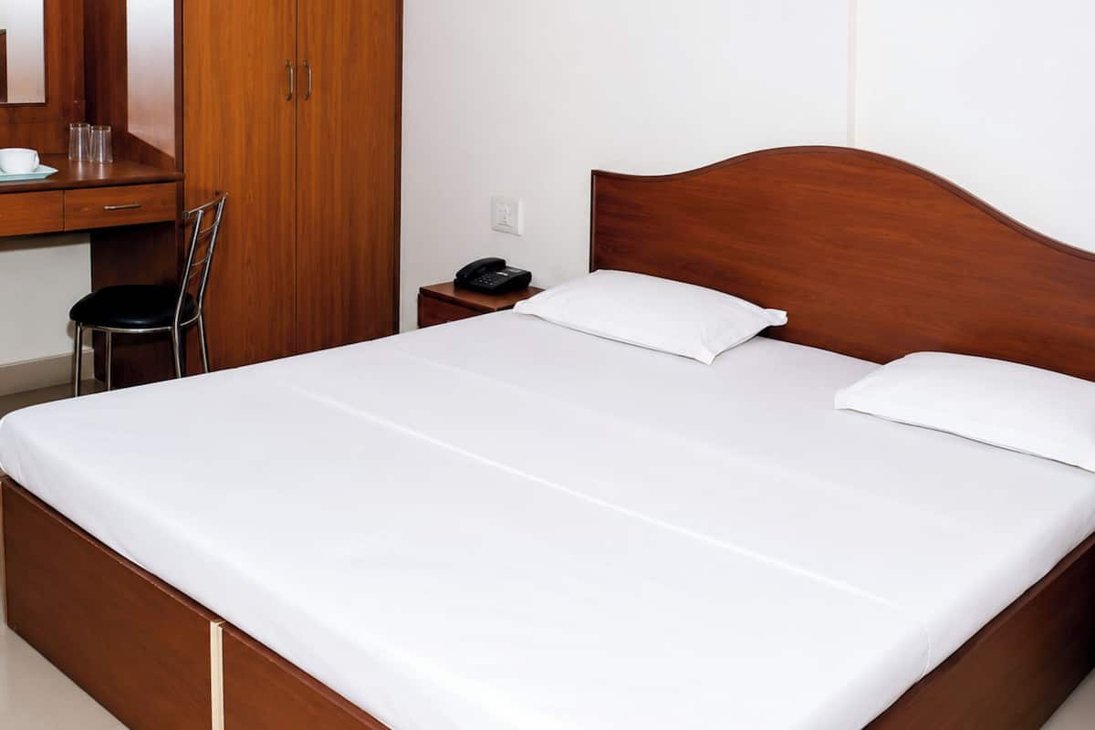 A bedroom with a wooden bed, a desk with a chair, and a wardrobe.