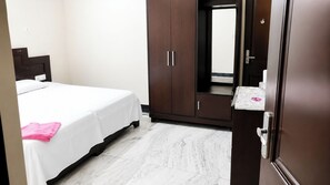 A hotel room with a bed, a wardrobe, a mirror, and a small table with toiletries. - Hotel Maharaja Palace AGRA (Agra)
