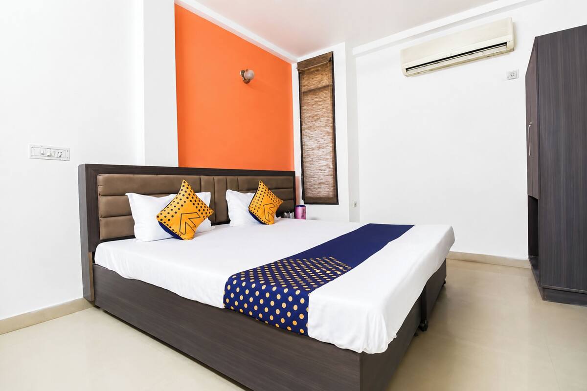 A bedroom with a bed, an air conditioning unit, and a wardrobe.