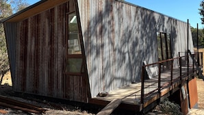 Un pequeño edificio rústico con techo inclinado y terraza de madera.