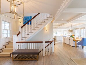 A spacious interior with a staircase, wooden flooring, and a dining area with chairs and a table.
