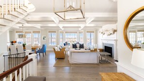 A spacious living area with a staircase, a dining area, and a fireplace.