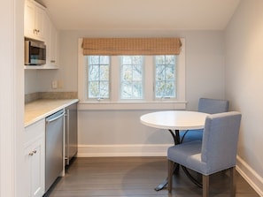A kitchen with a dining table and chairs, a window with blinds, and a microwave above the counter. - 8BR Pondfront Estate with Ocean Views, Pool, Spa, Tennis and Golf Club Access (Nantucket)