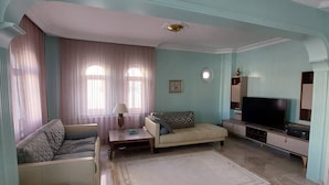A living room with a sofa, a coffee table, a TV, and a small table. - Tranquil 3-bedroom House in Eğirdir With Stunning Views (Egirdir)
