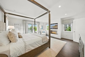 A four-poster bed with a fireplace, a television, and a view of the outdoors.