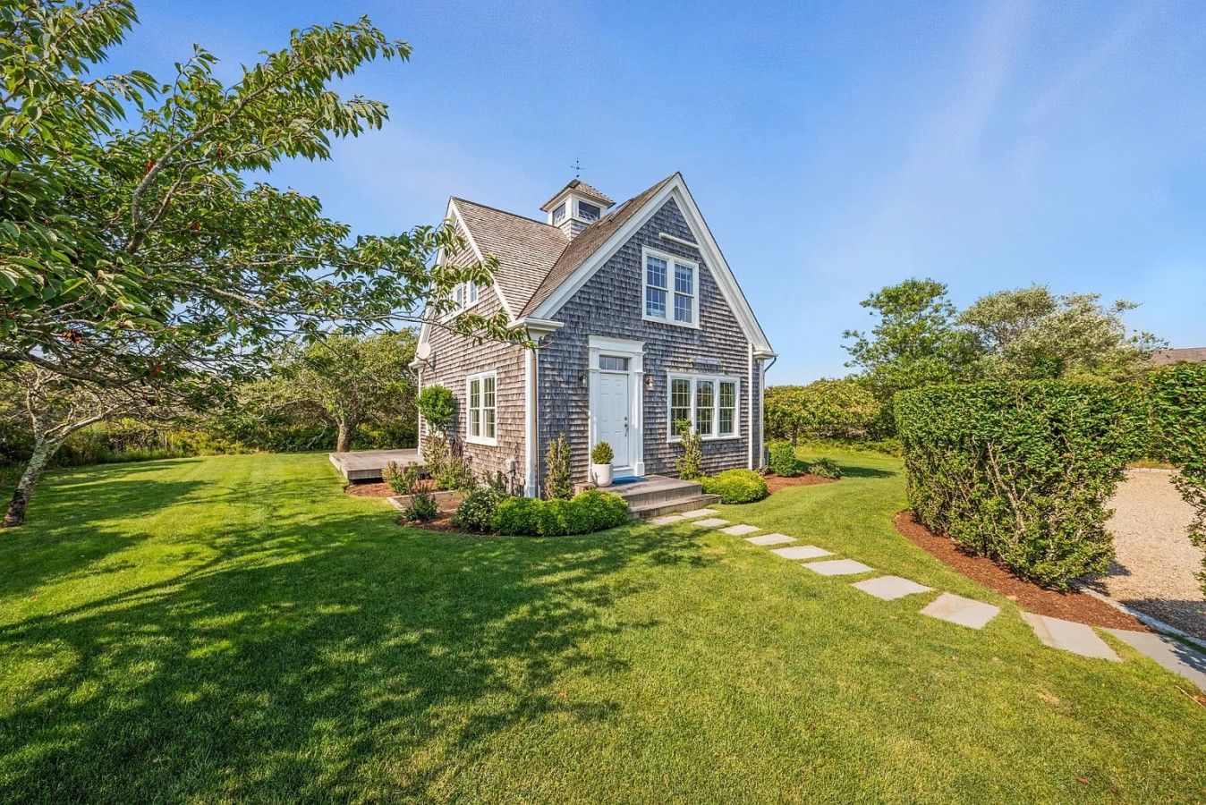 Une maison à deux étages avec un porche à l’avant, une pelouse bien entretenue et une allée gravillonnée.