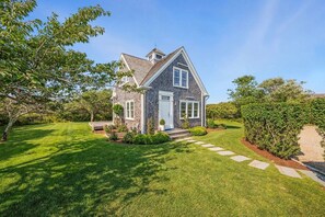 A two-story house with a front porch, a well-maintained lawn, and a gravel driveway.