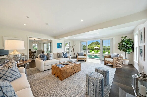 A spacious living room with a large window, a sofa, a coffee table, and a dining area.